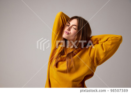 Half-length portrait of fashionable sensual emotional woman wearing trendy yellow sweater posing over gray background. Concept of fashion, style, youth, beauty Half-length portrait of fashionable sensual emotional woman wearing trendy yellow sweater posing over gray background. Concept of fashion, style, youth, beauty 98507389