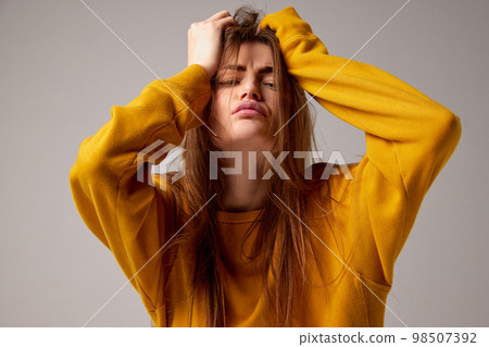 Half-length portrait of fashionable sensual emotional woman wearing trendy yellow sweater posing over gray background. Concept of fashion, style, youth, beauty 98507392