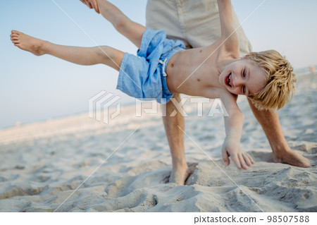 Father holding his son upside down, enjoying summer vacation, having fun. Father holding his son upside down, enjoying summer vacation, having fun. 98507588