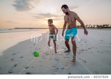 Father with his son plaing football on the beach. Father with his son plaing football on the beach. 98507609