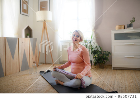 Pregnant woman doing exercises in her apartment. Pregnant woman doing exercises in her apartment. 98507731