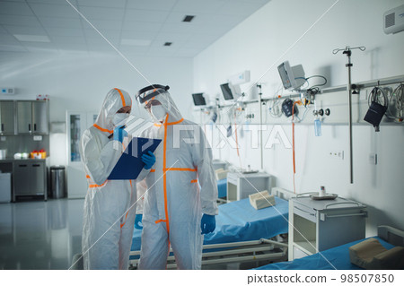 Doctors in protective coveralls in hospital room, infectious disease concept. 98507850