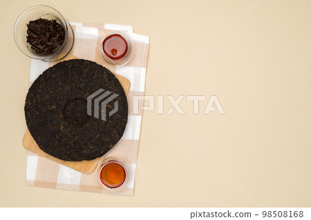 Black puer tea, dry pu erh tea leaves on a beige background. Fermented and aged dark tea, copy space 98508168