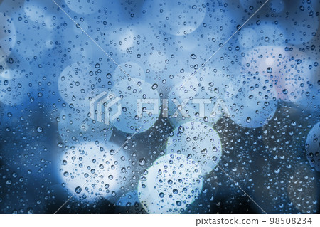 Abstract background with raindrops and soft blue bokeh. Defocused lights and water droplets on rainy wet window. Street bokeh lights out of focus. Rainy days, weather concept. View through window 98508234