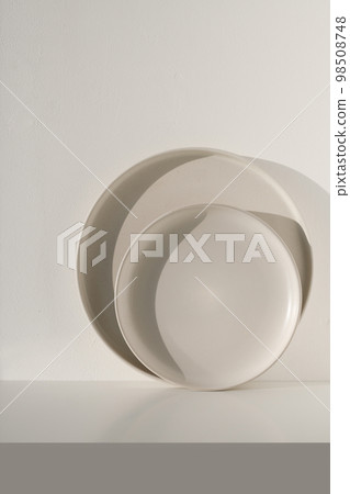 Two beige ceramic plates on a light background on a sunny day. Natural lighting 98508748