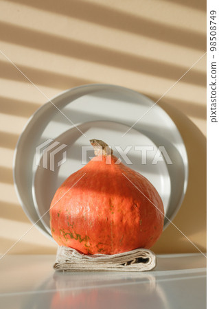 a whole pumpkin on a background of beige plates and beige background with shadows 98508749