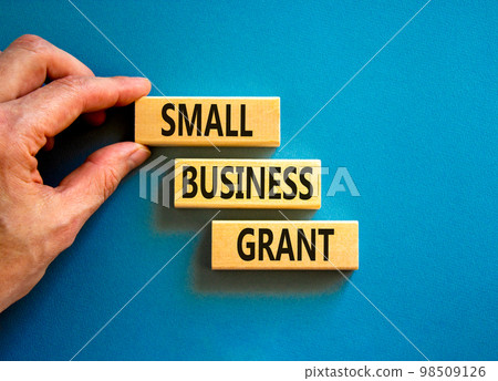 Small business grant symbol. Concept words Small business grant on wooden blocks on a beautiful blue table blue background. Businessman hand. Business, finacial and small business grant concept. 98509126