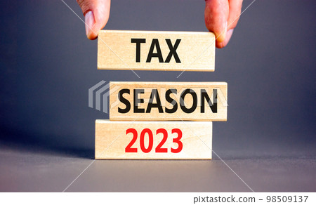 Tax season 2023 symbol. Concept words Tax season 2023 on wooden blocks on a beautiful grey table grey background. Businessman hand. Business Tax season 2023 concept. Copy space. 98509137