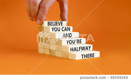 You can symbol. Concept words Believe you can and you are halfway there on wooden blocks on a beautiful orange table orange background. Businessman hand. Business motivational and you can concept. 98509268