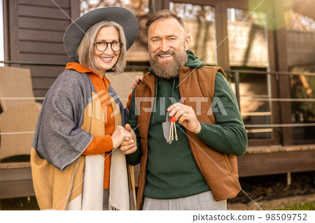 Happy man and woman standing near their new house and smiling 98509752