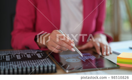 Businesswoman analyzing graphs using digital tablet and stylus at office. 98510826