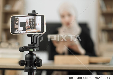 Focus on phone screen , muslim woman recording video on phone camera while unpacking box 98510955