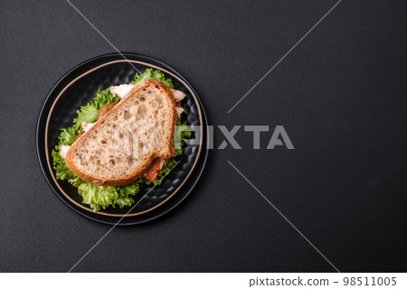 Fresh tasty sandwich with chicken, tomatoes and lettuce on a black plate 98511005