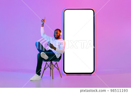Cheerful african american man using smartphone and wireless headphones, mockup 98511193