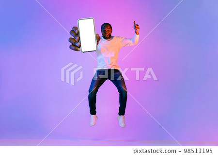 Excited african american man jumping in the air with smartphone 98511195