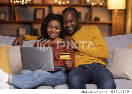 Happy black couple banking from home, using laptop, credit card 98511199