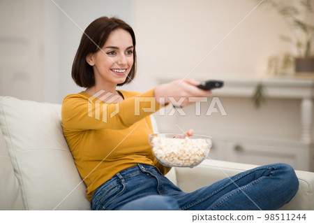 Young woman watching TV, movies with popcorn at home 98511244