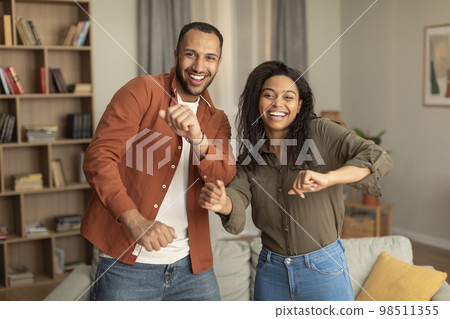Joyful african american spouses having fun and dancing together, celebrating move or anniversary in living room interior Joyful african american spouses having fun and dancing together, celebrating move or anniversary in living room interior 98511355