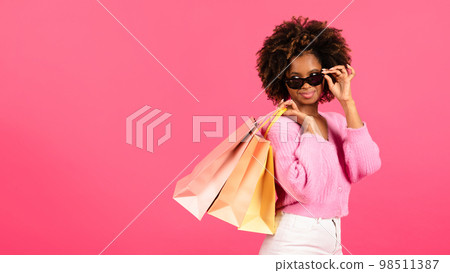 Cheerful millennial african american curly female shopaholic takes off glasses hold many packages Cheerful millennial african american curly female shopaholic takes off glasses hold many packages 98511387