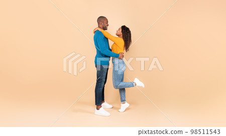 Couple in love. African american spouses hugging, standing over peach background, panorama, side view, full length shot 98511543