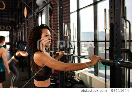 Athletic african american woman in crossfit gym close up smiling leaning on a barbell. Athletic african american woman in crossfit gym close up smiling leaning on a barbell. 98511644