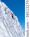 A climber in a red suit climbs an icy white mountain 98513270
