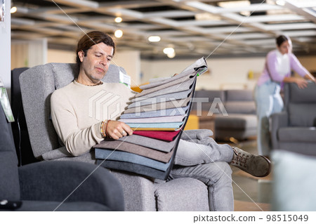 Man picking upholstery material in furniture store 98515049