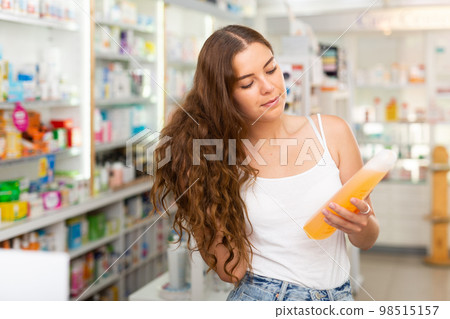 Young woman who came to the pharmacy chooses a hair care remedy 98515157