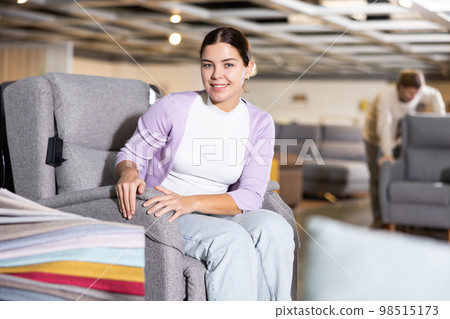 Girl checks high quality of armchair in furniture store Girl checks high quality of armchair in furniture store 98515173