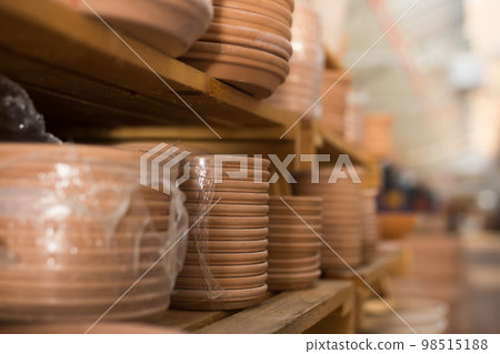 Stacks of ceramic plates for flower pots on shekves in store Stacks of ceramic plates for flower pots on shekves in store 98515188