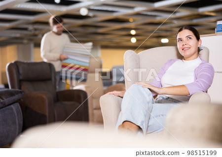 Girl checks high quality of armchair in furniture store Girl checks high quality of armchair in furniture store 98515199