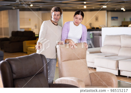 Man and woman looking to buy armchair in furniture store 98515217