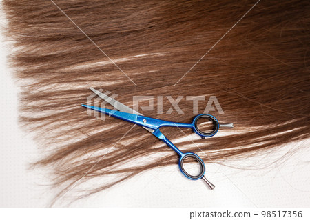 Scissors lie on the hair ribbon for extension at home. Scissors lie on the hair ribbon for extension at home. 98517356