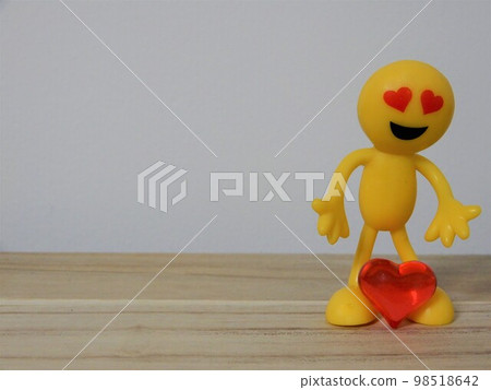 A yellow doll standing with a red heart between its legs 98518642