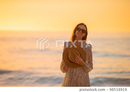 Young beautiful woman at straw hat on the beach at sunset Young beautiful woman at straw hat on the beach at sunset 98518919