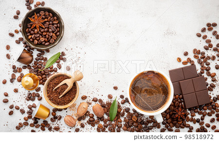 Background of various coffee , dark roasted coffee beans , ground and capsules with scoops setup on white concrete background with copy space. Background of various coffee , dark roasted coffee beans , ground and capsules with scoops setup on white concrete background with copy space. 98518972