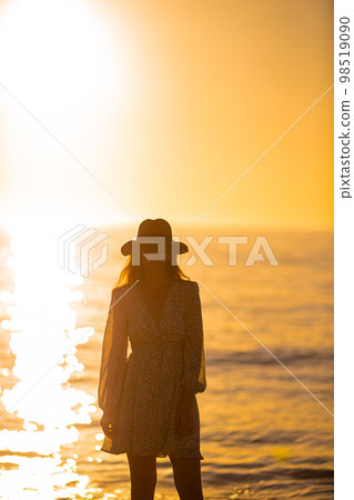 Young beautiful woman at straw hat on the beach at sunset Young beautiful woman at straw hat on the beach at sunset 98519090