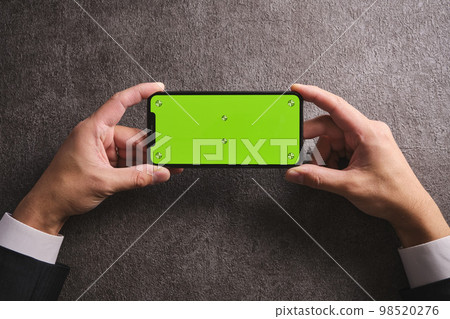 Holding a smartphone with both hands Black concrete center 98520276