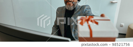 Smiling bearded man in headphones demonstrating a gift 98521756