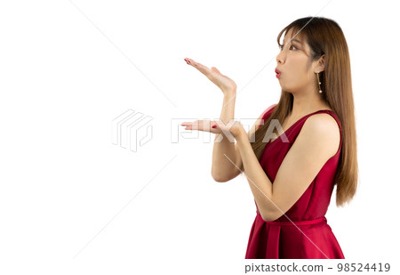 Asian woman in red elegant dress smiling and hand pointing on white background. Happy Valentine. 98524419
