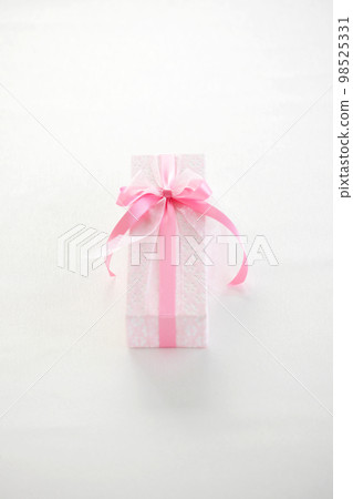 Image of a gift A gift box wrapped in pale pink wrapping paper and a ribbon 98525331