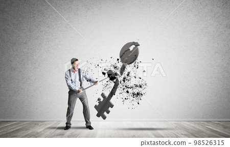 Breaking through access concept with man in room crashing concrete key 98526315