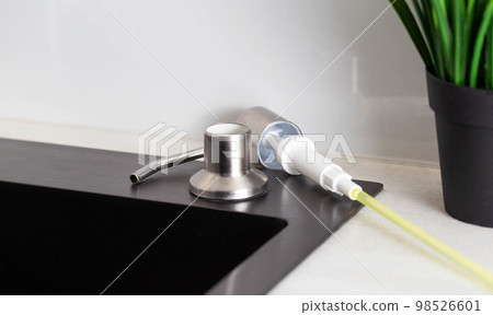 Dismantled detergent dispenser built into the sink. Adding soap to the dispenser. Copy space for text 98526601