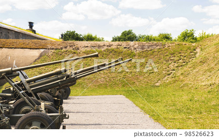 Military guns installed on the street against the backdrop of a bomb shelter. Military conflict, aggression. Copy space for text 98526623