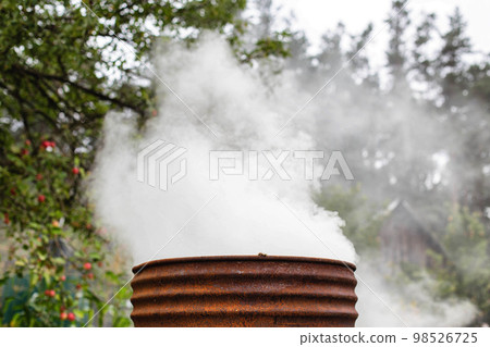 Burning dry grass and garbage in the country in the fall in an iron barrel. Penalty and fire hazard if weed is burned incorrectly. A lot of smoke Burning dry grass and garbage in the country in the fall in an iron barrel. Penalty and fire hazard if weed is burned incorrectly. A lot of smoke 98526725