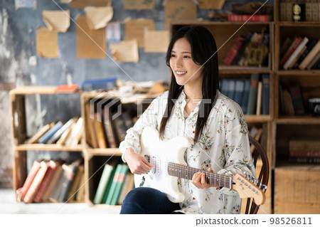 A young lady playing the guitar 98526811