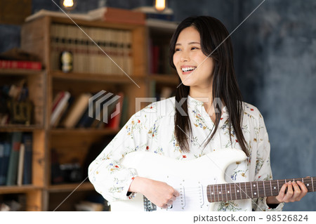 A young lady playing the guitar 98526824