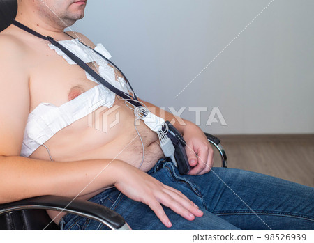 An obese man undergoes a Holter monitoring of the heart. Control of blood supply and disorders of the heart after myocardial infarction, electrocardiogram An obese man undergoes a Holter monitoring of the heart. Control of blood supply and disorders of the heart after myocardial infarction, electrocardiogram 98526939