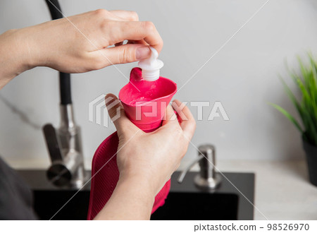 A woman twists a cork in a medical heating pad. Heat treatment, close-up A woman twists a cork in a medical heating pad. Heat treatment, close-up 98526970