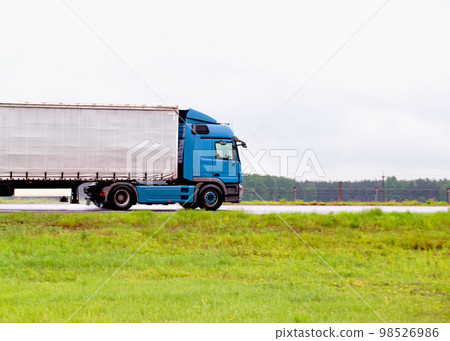 A truck with a semi-trailer transports cargo in rainy weather on a slippery road. Automobile cargo transportation. Copy space for text A truck with a semi-trailer transports cargo in rainy weather on a slippery road. Automobile cargo transportation. Copy space for text 98526986